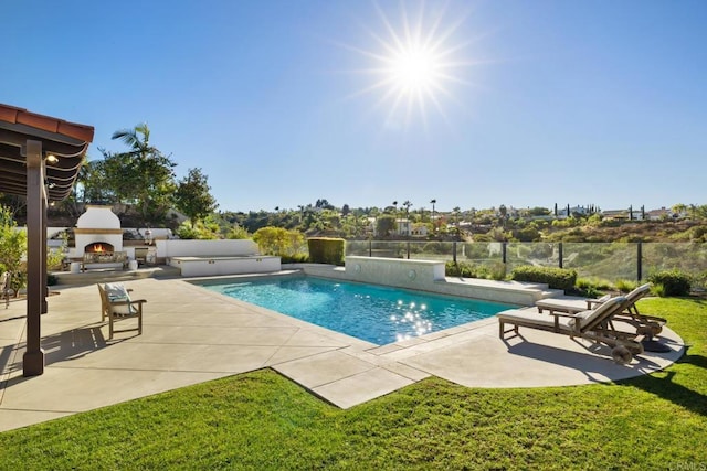 view of swimming pool featuring exterior fireplace, a yard, and a patio