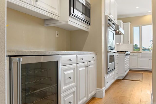 kitchen with light hardwood / wood-style floors, white cabinetry, beverage cooler, and stainless steel microwave