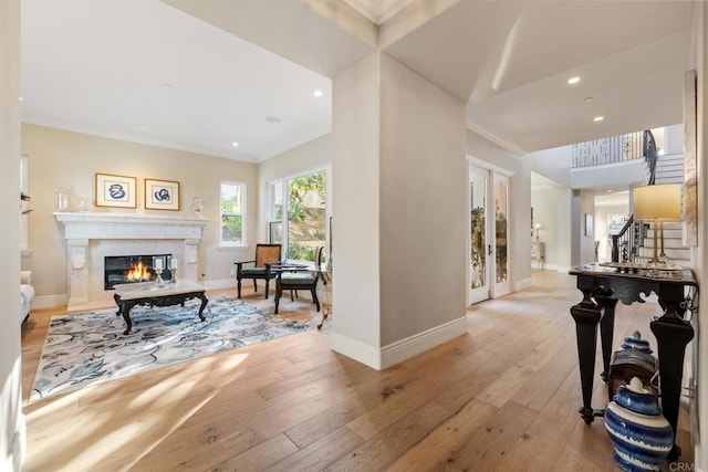 hallway featuring light hardwood / wood-style floors, crown molding, and french doors