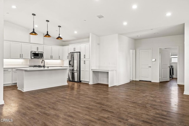 kitchen with white cabinetry, hanging light fixtures, stainless steel appliances, and a kitchen island with sink