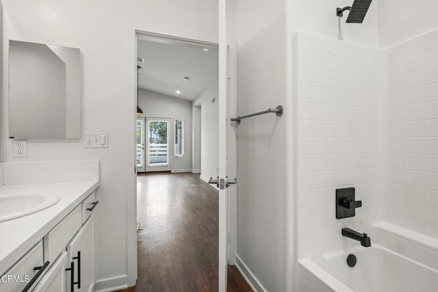 bathroom featuring washtub / shower combination, vaulted ceiling, hardwood / wood-style flooring, and vanity