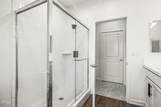 bathroom with an enclosed shower, vanity, and wood-type flooring