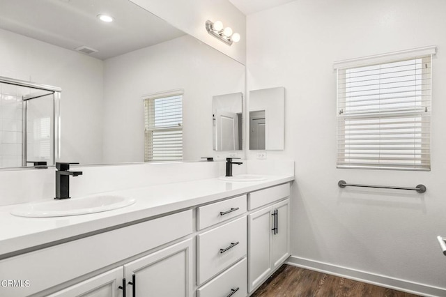 bathroom with hardwood / wood-style flooring, a shower with shower door, and vanity