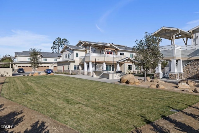 view of front facade with a balcony, a patio area, and a front lawn