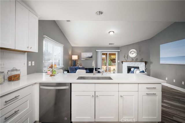 kitchen with kitchen peninsula, white cabinetry, stainless steel dishwasher, and sink