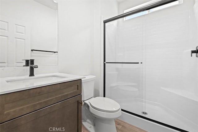 bathroom featuring toilet, an enclosed shower, and vanity