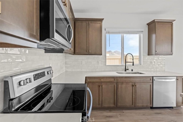 kitchen featuring light hardwood / wood-style floors, sink, decorative backsplash, and stainless steel appliances