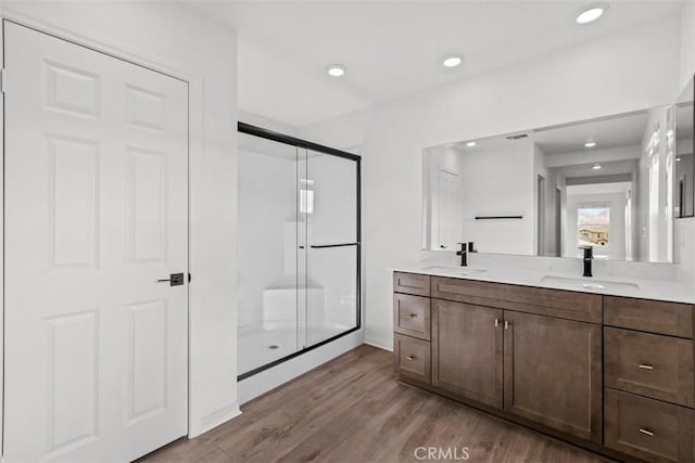 bathroom with walk in shower, vanity, and wood-type flooring