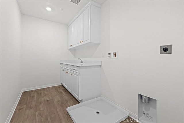 clothes washing area featuring electric dryer hookup, light wood-type flooring, hookup for a washing machine, cabinets, and sink