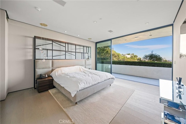 bedroom featuring access to outside, multiple windows, floor to ceiling windows, and light hardwood / wood-style floors