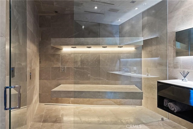 bathroom with walk in shower, vanity, and tile walls