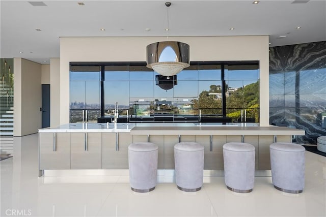 kitchen featuring decorative light fixtures, sink, and a large island with sink