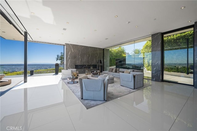 living room with a high end fireplace, light tile patterned floors, and a wall of windows