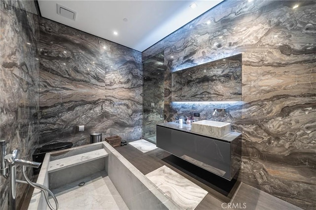 bathroom featuring vanity and tile walls