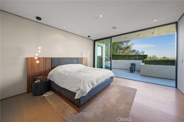 bedroom with access to outside, expansive windows, and light hardwood / wood-style floors