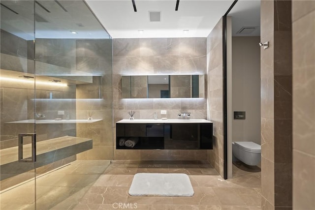 bathroom with vanity, toilet, tile walls, and a shower with shower door