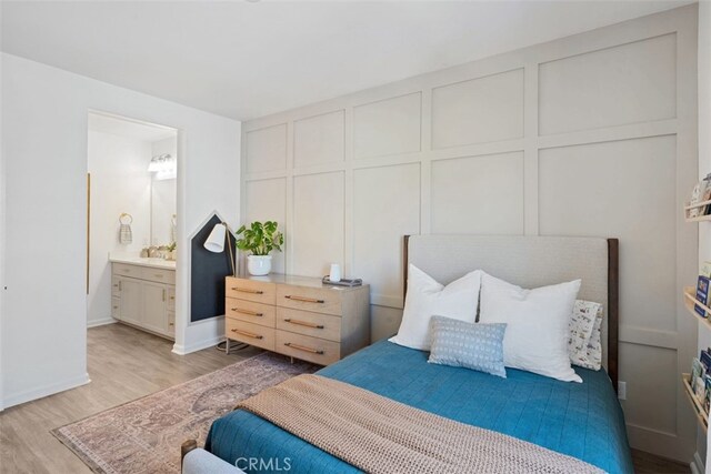 20 Jaripol Cir, Rancho Mission Viejo, CA 92694 - bedroom featuring a decorative wall, ensuite bath, light wood-type flooring, and baseboards