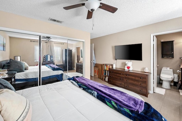 bedroom with ceiling fan, ensuite bathroom, a textured ceiling, and a closet