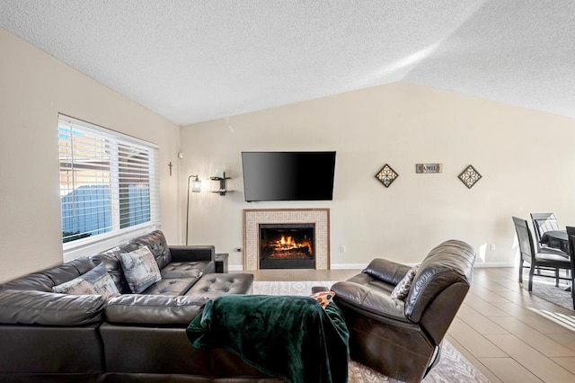 living room with a textured ceiling, a tiled fireplace, and lofted ceiling