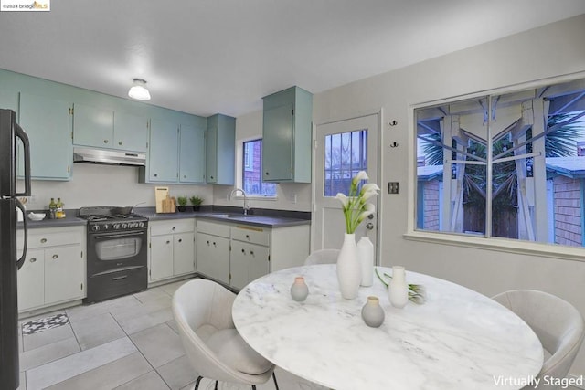 kitchen with black gas range, light tile patterned floors, and sink