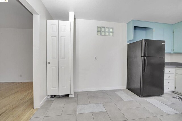 kitchen with black refrigerator, light hardwood / wood-style floors, and blue cabinets