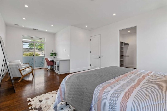 bedroom with a spacious closet and dark hardwood / wood-style flooring