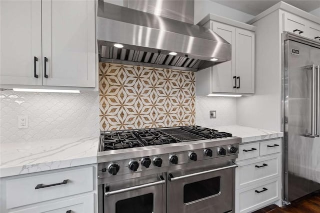 kitchen with extractor fan, high quality appliances, white cabinets, decorative backsplash, and light stone counters