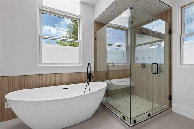 bathroom featuring tile patterned flooring, separate shower and tub, and wooden walls