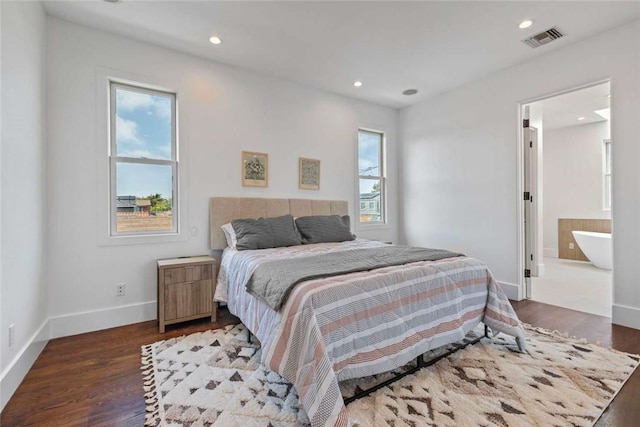 bedroom with multiple windows, ensuite bathroom, and dark hardwood / wood-style flooring