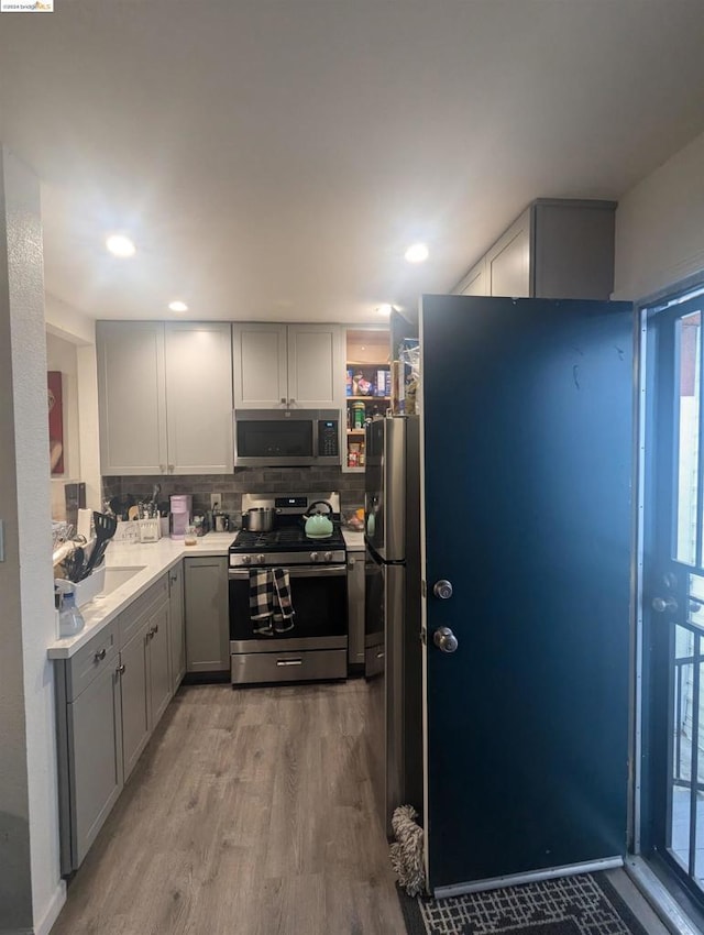 kitchen featuring stainless steel appliances, a wealth of natural light, light hardwood / wood-style floors, and gray cabinetry