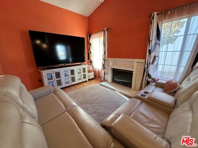 living room featuring a brick fireplace, vaulted ceiling, and hardwood / wood-style flooring