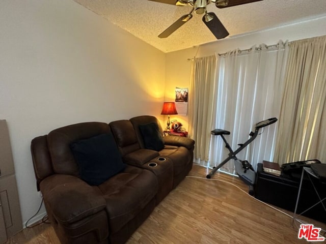 living room featuring ceiling fan, hardwood / wood-style floors, and a textured ceiling