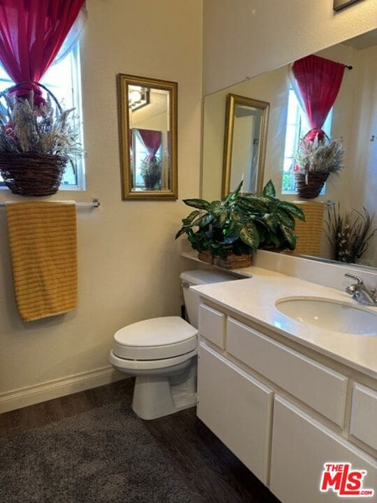 bathroom with wood-type flooring, vanity, toilet, and plenty of natural light