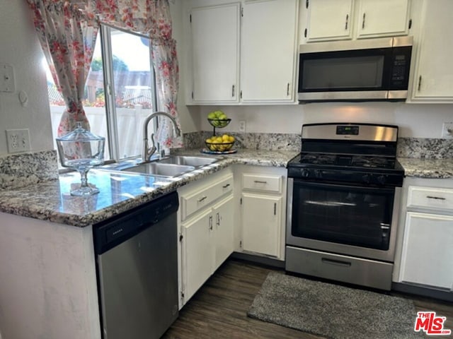 kitchen with appliances with stainless steel finishes, white cabinetry, dark wood-type flooring, and sink