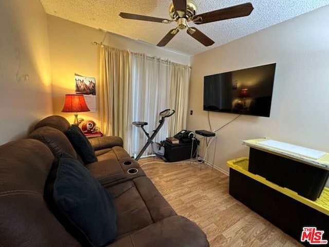 living room with ceiling fan, light hardwood / wood-style flooring, and a textured ceiling