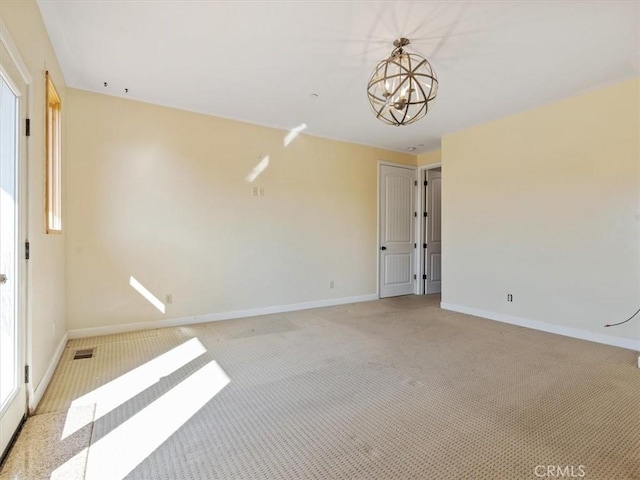 unfurnished room featuring light carpet and a notable chandelier