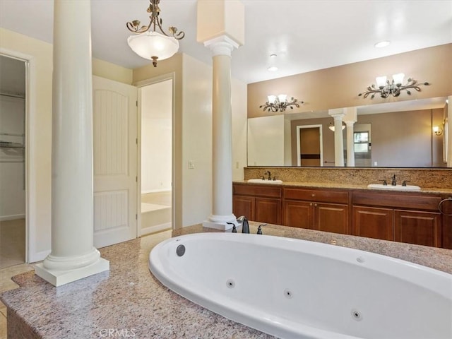 bathroom with vanity, tiled bath, and ornate columns