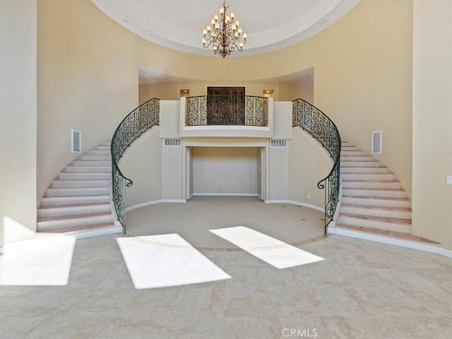 foyer entrance featuring a raised ceiling, a chandelier, and a high ceiling