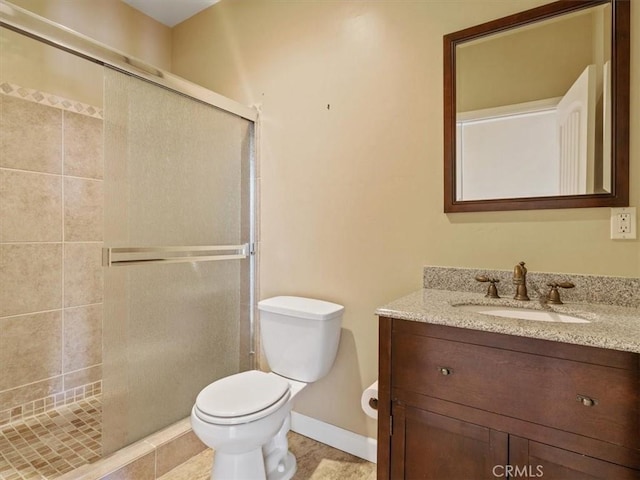 bathroom with vanity, a shower with door, and toilet