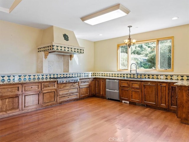 kitchen featuring pendant lighting, sink, a notable chandelier, wood-type flooring, and stainless steel gas cooktop