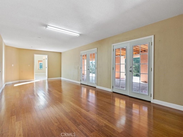 unfurnished room featuring french doors, hardwood / wood-style floors, and a textured ceiling