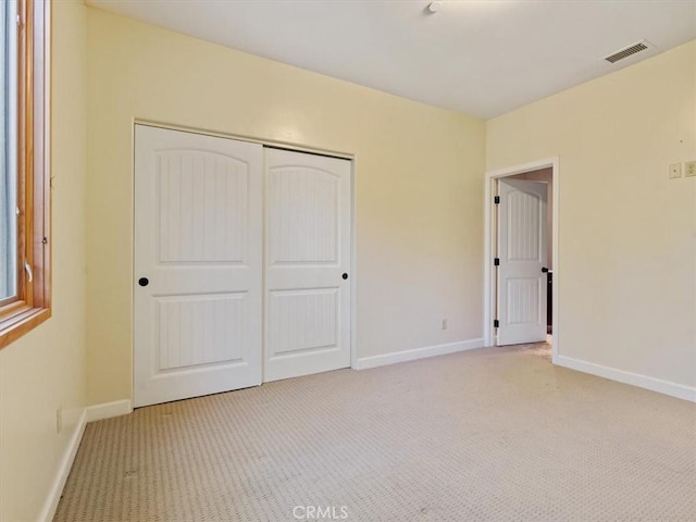 unfurnished bedroom with a closet and light carpet