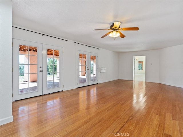 spare room featuring light hardwood / wood-style flooring, ceiling fan, and french doors