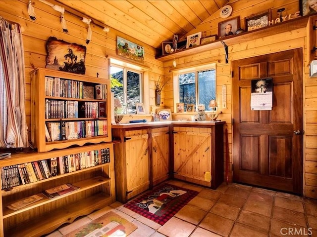 interior space featuring wood walls, lofted ceiling, light tile patterned floors, and wooden ceiling