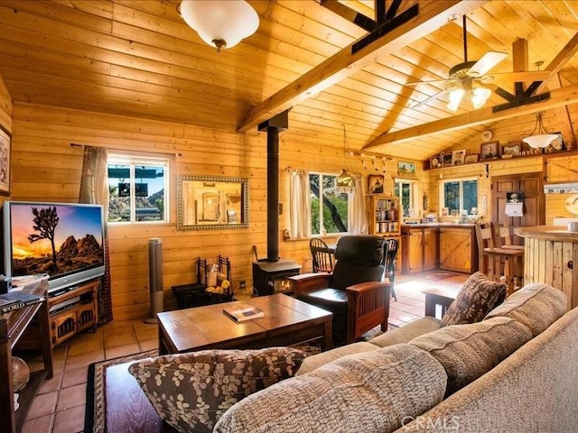 tiled living room featuring lofted ceiling with beams, a wood stove, a healthy amount of sunlight, and wood ceiling