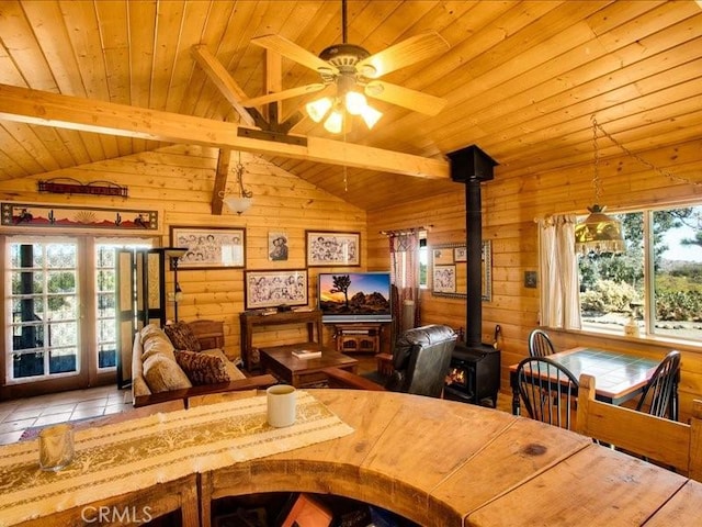 tiled dining area featuring vaulted ceiling with beams, a wood stove, wood ceiling, and wood walls