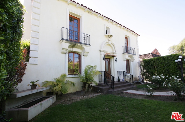 exterior space with a balcony and a front yard