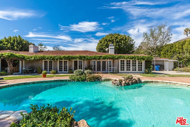 view of pool with french doors and a patio area