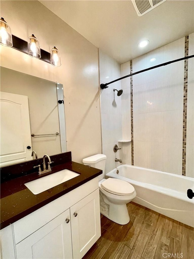 full bathroom featuring vanity, toilet, wood-type flooring, and tiled shower / bath