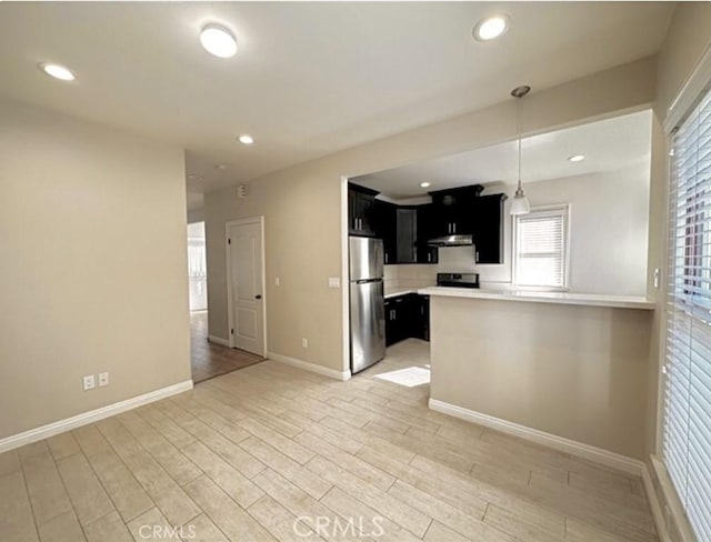 kitchen with kitchen peninsula, light wood-type flooring, stainless steel refrigerator, and hanging light fixtures